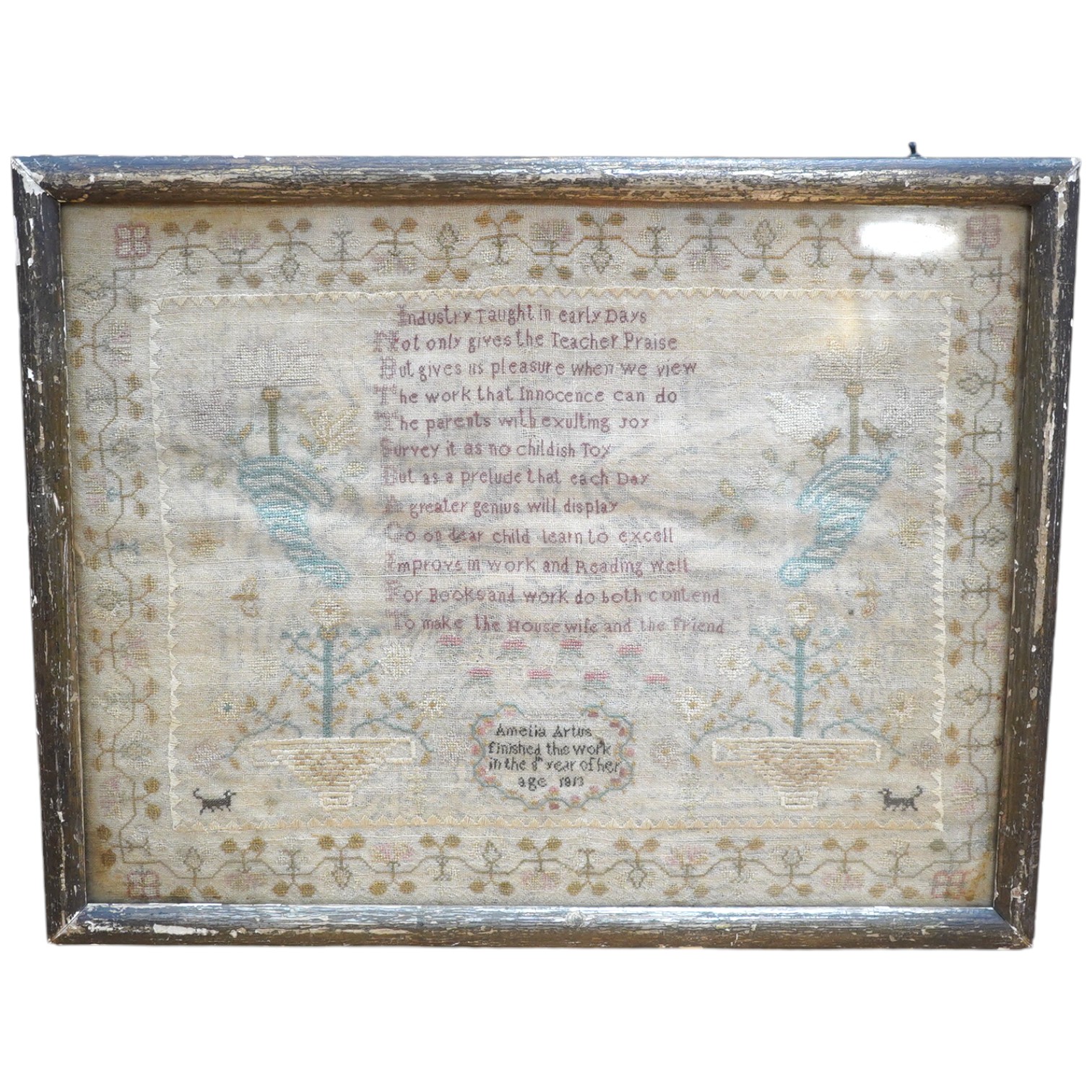 A gilt framed finely worked Regency gauze sampler, by Amelia Artus, aged 8 years, dated 1813, worked on fine gauze with coloured silk threads, with a large central panel having a long verse, two motifs of cornucopia, pot